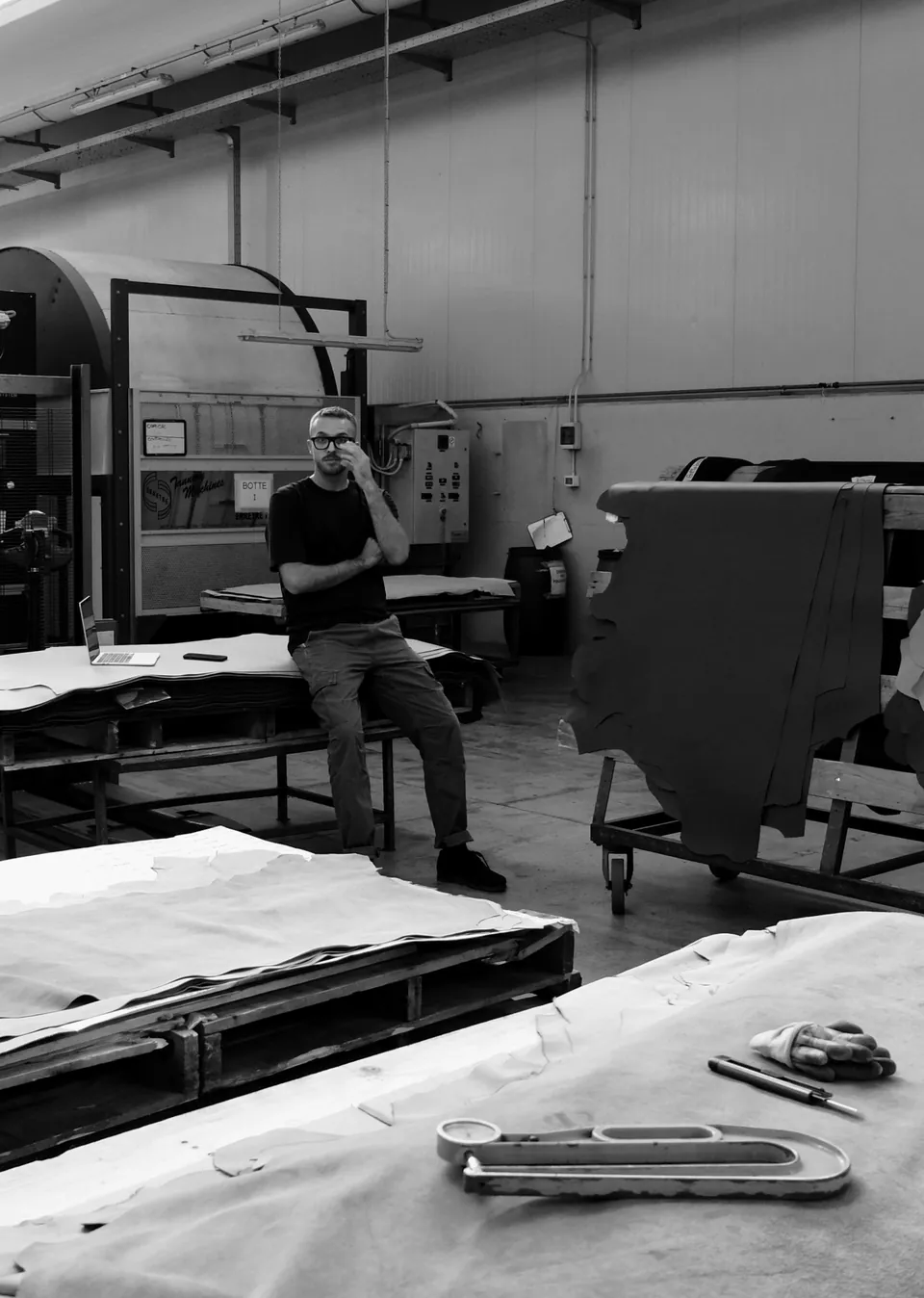 Alberto Lovato in a tannery, sitting on a stack of hides among the processing machines